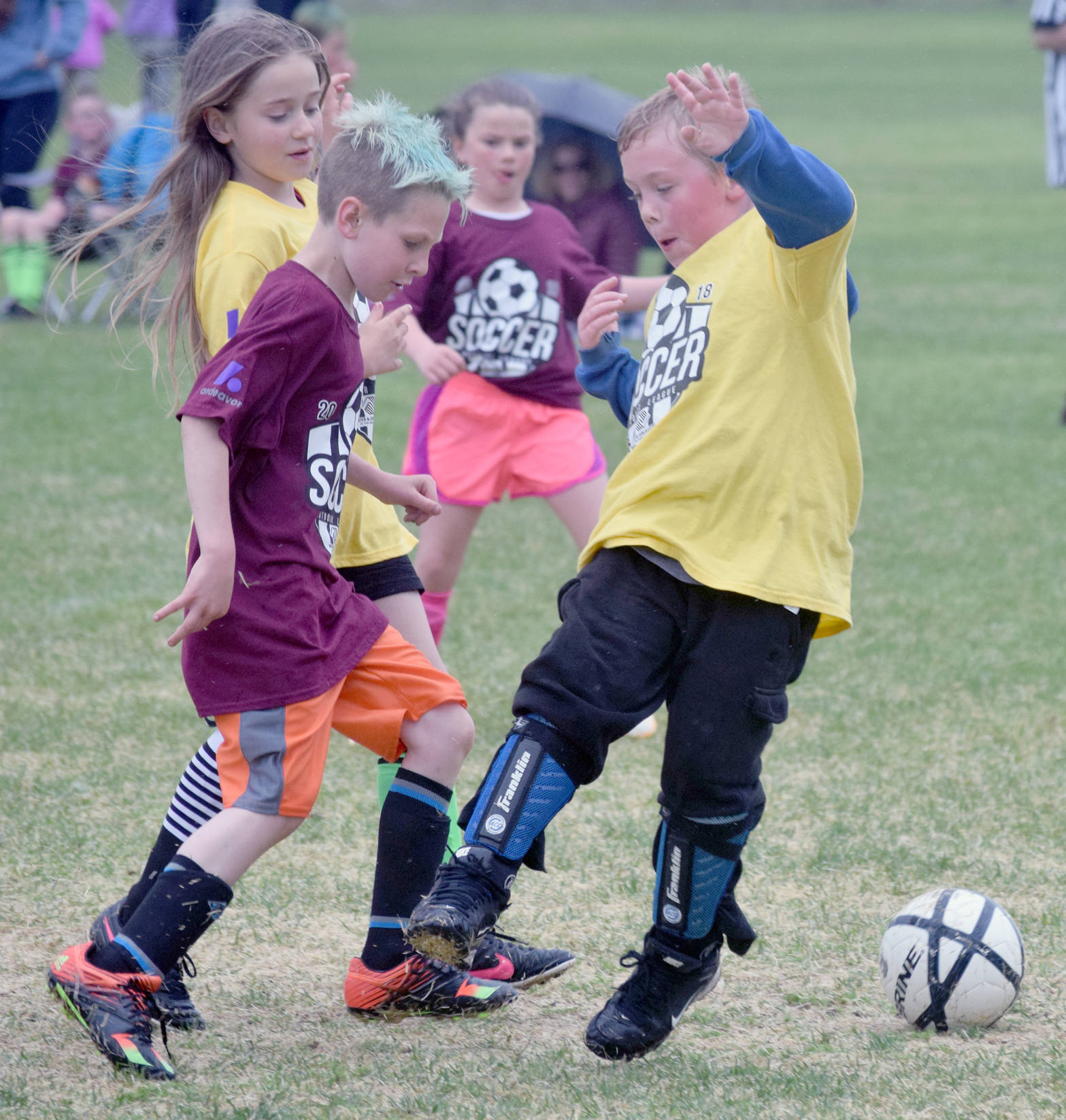 Eamon Traxler (in maroon) dribbles between Amy Sevast and Elijah Stanton on Tuesday, June 19, 2018, in Boys and Girls Club soccer at Kenai Middle School. (Photo by Jeff Helminiak/Peninsula Clarion)