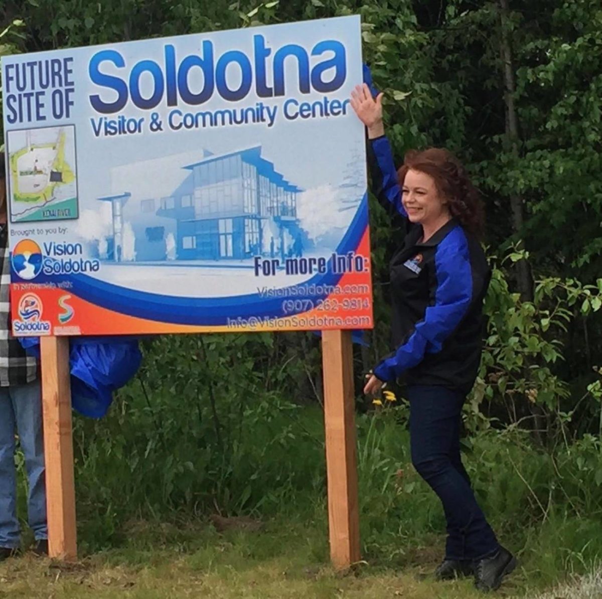 Shanon Davis, executive director of the Soldotna Chamber of Commerce, unveils a new sign indicating the future site of the proposed Soldotna visitor and community center, Wednesday, June 27 in Soldotna, Alaska. (Photo by Victoria Petersen/Peninsula Clarion)
