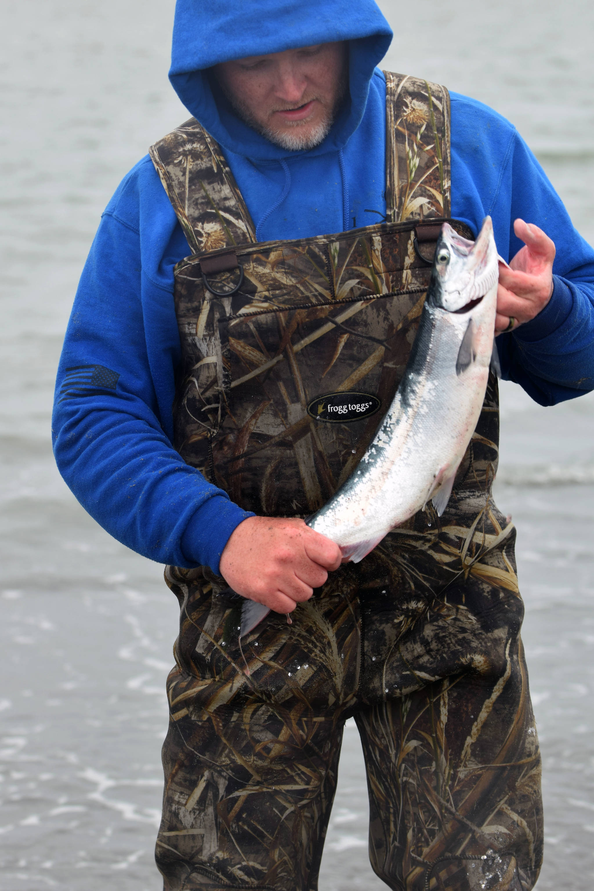 Derrick Milburn shows off a salmon on Kenai Beach on the opening day of the dipnetting season on July 10, 2018, in Kenai, Alaska. Milburn traveled with his two sons from Fort Richardson to attend the opening day of the season. Milburn said the catch was less bountiful this year than in years past, but had snagged two salmon and six flounder by mid-afternoon Tuesday. (Photo by Erin Thompson/Peninsula Clarion)
