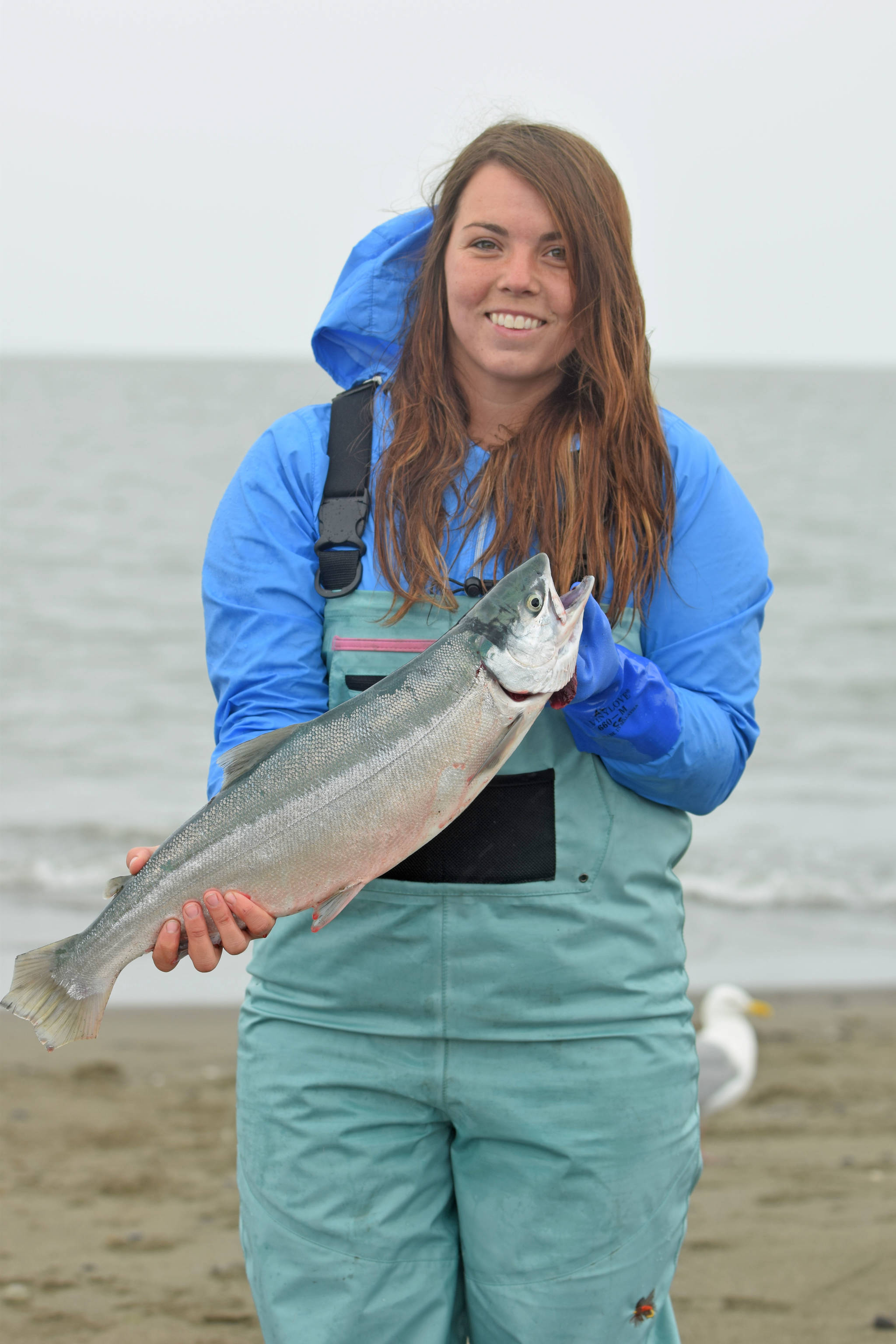 Alaina Hager shows off her catch on Kenai Beach during the first day of the three-week dipnetting season on July 10, 2018, in Kenai, Alaska. Hager, who was dipnetting for the first time, had caught two salmon and a flounder by mid-afternoon Tuesday. (Photo by Erin Thompson/Peninsula Clarion)