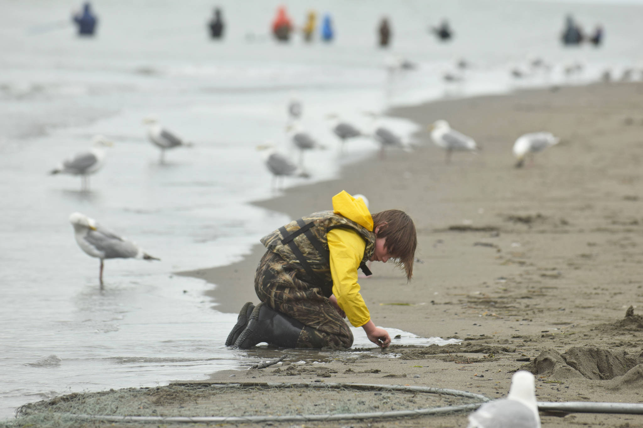 A young boy distracts himself in the Kenai Beach sand on Tuesday, July 10, 2018, during the first day of the dipnetting season. (Photo by Erin Thompson/Peninsula Clarion)