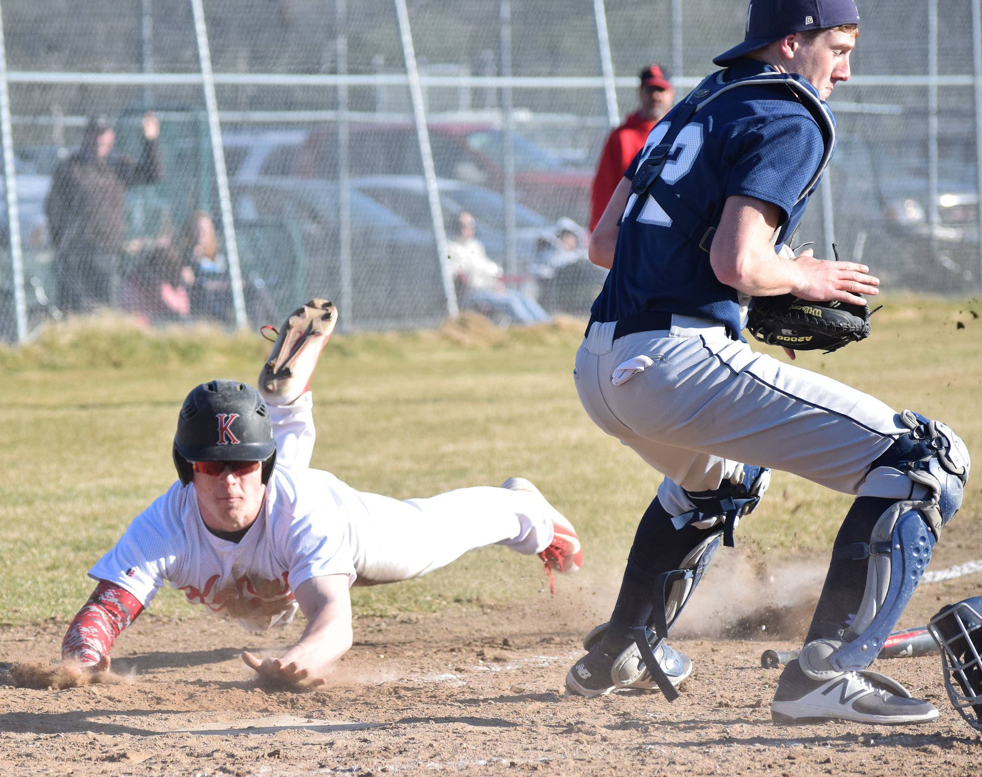 Kenai Central’s Paul Steffensen dives for home plate behind Soldotna catcher Cody Quelland to score a run in a high school contest May 10, 2017, at the Kenai Little League Fields. (Photo by Joey Klecka/Peninsula Clarion)