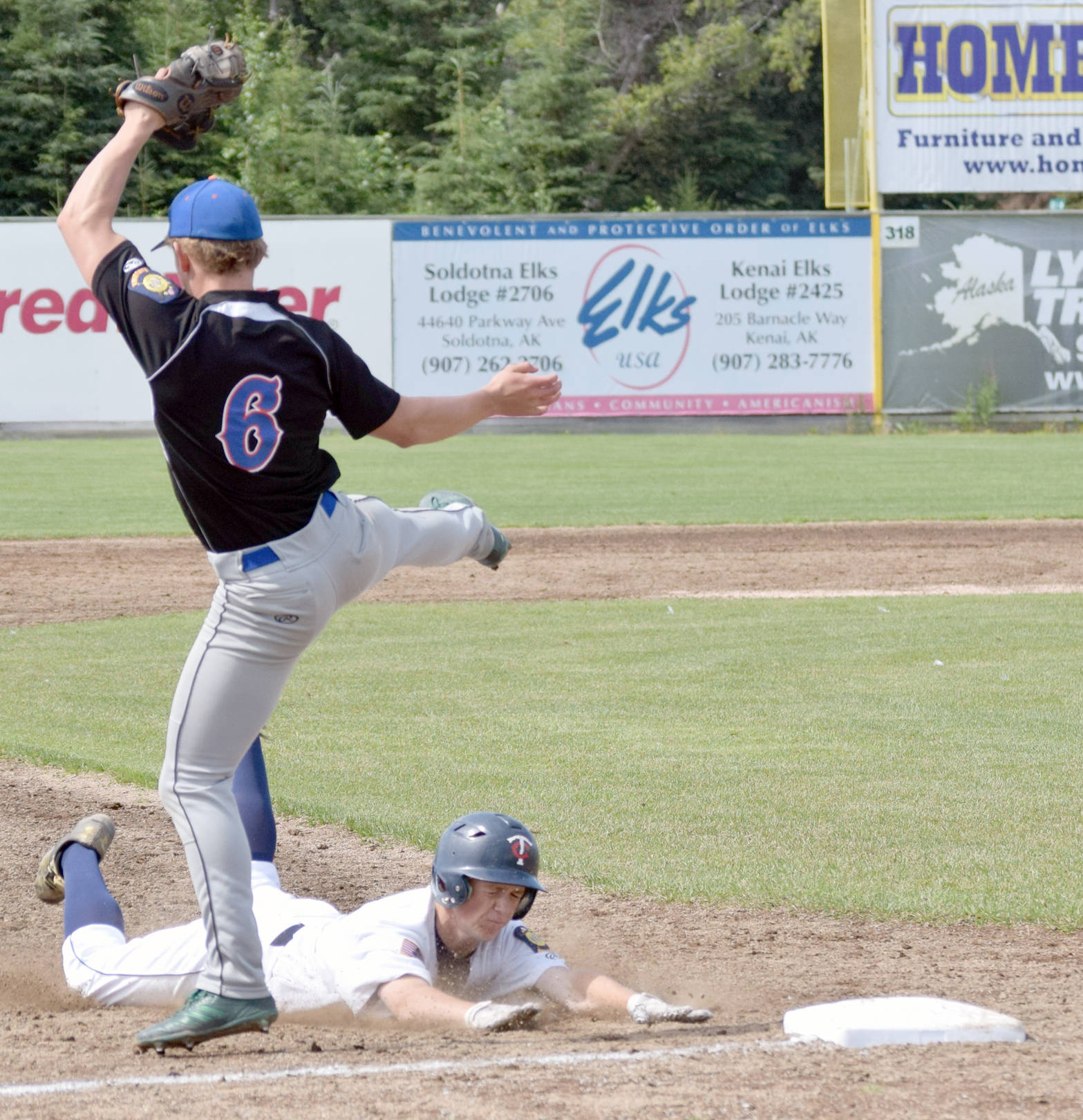 Harrison Metz of the Twins takes third base by sliding under Palmer third baseman Trace Severson on Sunday, July 15, 2018, at Coral Seymour Memorial Park in Kenai. (Photo by Jeff Helminiak/Peninsula Clarion)