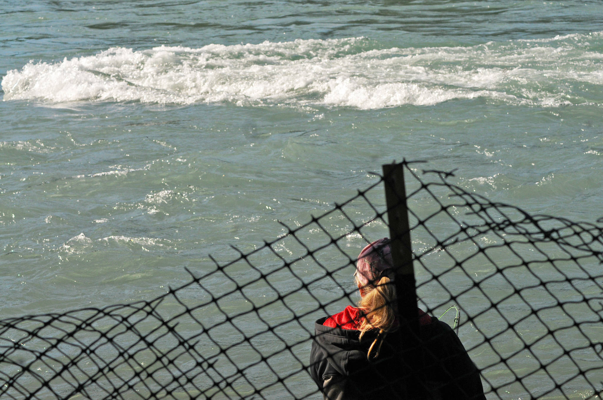 An angler casts her line into the Kenai River near Soldotna Creek Park on Wednesday, July 18, 2018 in Soldotna, Alaska. The water in the Kenai River is a little higher than usual — about 9.71 feet, according to U.S. Geological Survey’s gauge at Soldotna — but has fallen since last week and is significantly below the flood stage of 12 feet. Anglers were hitting the banks on Wednesday morning for sockeye salmon, which normally peak in returning numbers to the Kenai River in mid-July. (Photo by Elizabeth Earl/Peninsula Clarion)