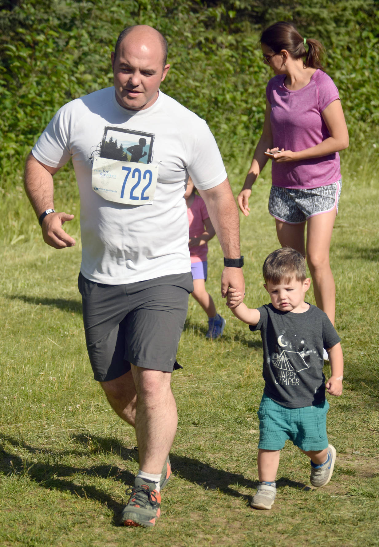 David Lorring helps his son, Wyatt, 2 1-2, during the one-kilometer kids race Wednesday, July 18, 2018, at the Salmon Run Series at Tsalteshi Trails. (Photo by Jeff Helminiak/Peninsula Clarion)