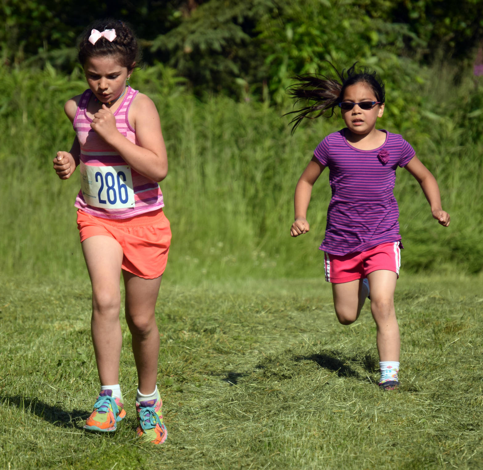Luci Salzer, 8, and Myka Battiest, 6, lead the one-kilometer kids race Wednesday, July 18, 2018, at the Salmon Run Series at Tsalteshi Trails. (Photo by Jeff Helminiak/Peninsula Clarion)