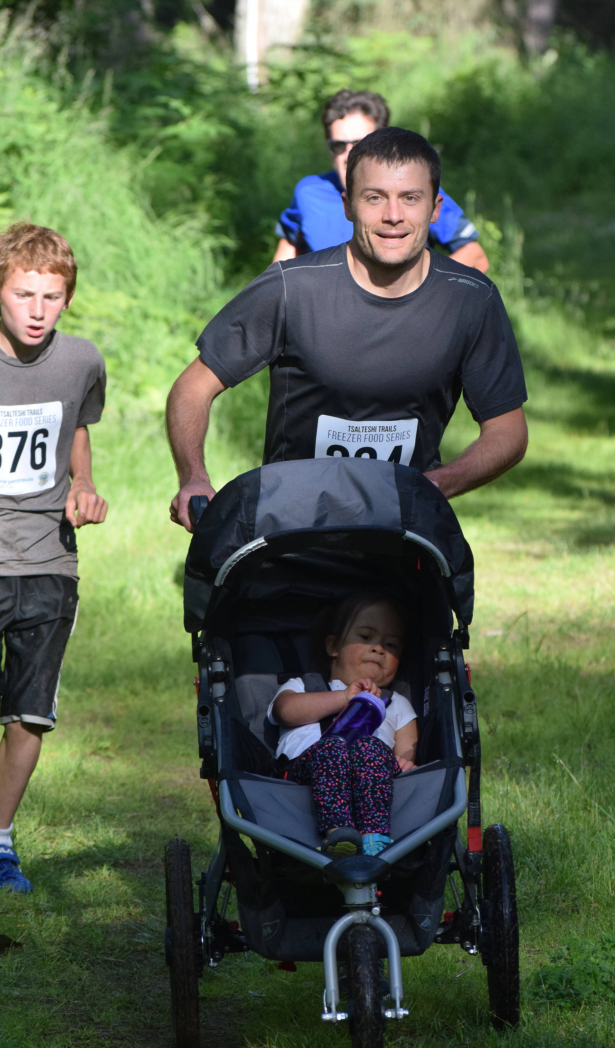 Jake Streich pushes the family stroller Saturday morning in the 10-kilometer race at the Soldotna Rotary Run at the Tsalteshi Trails. (Photo by Joey Klecka/Peninsula Clarion)