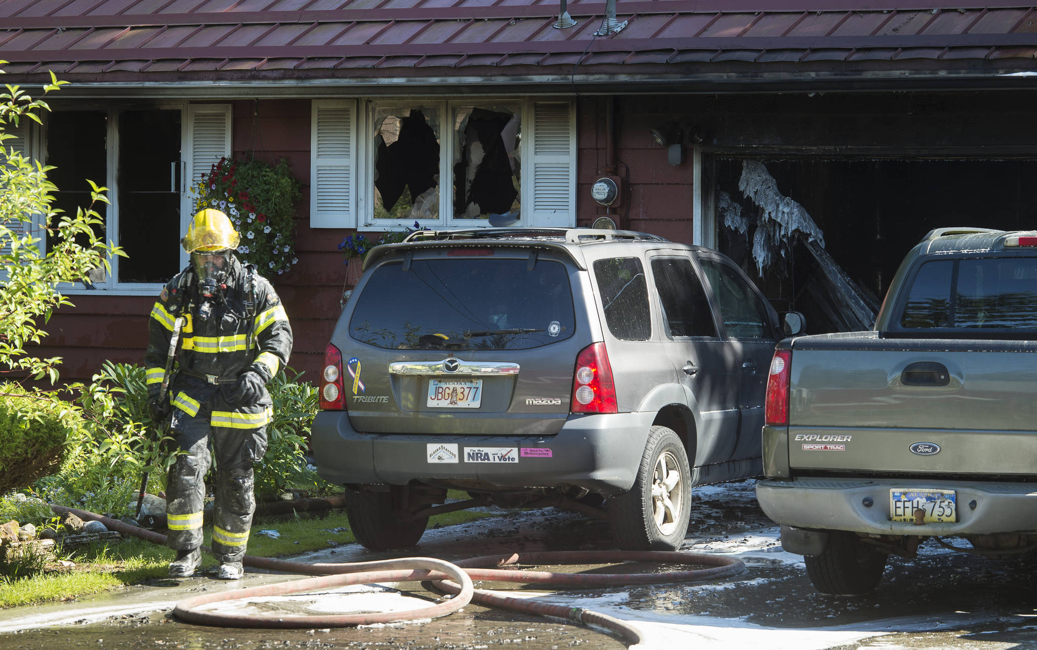A Capital City Fire/Rescue fireman walks away after fighting a house fire at 8460 Kimberly Street on Friday, July 20, 2018. (Michael Penn | Juneau Empire)