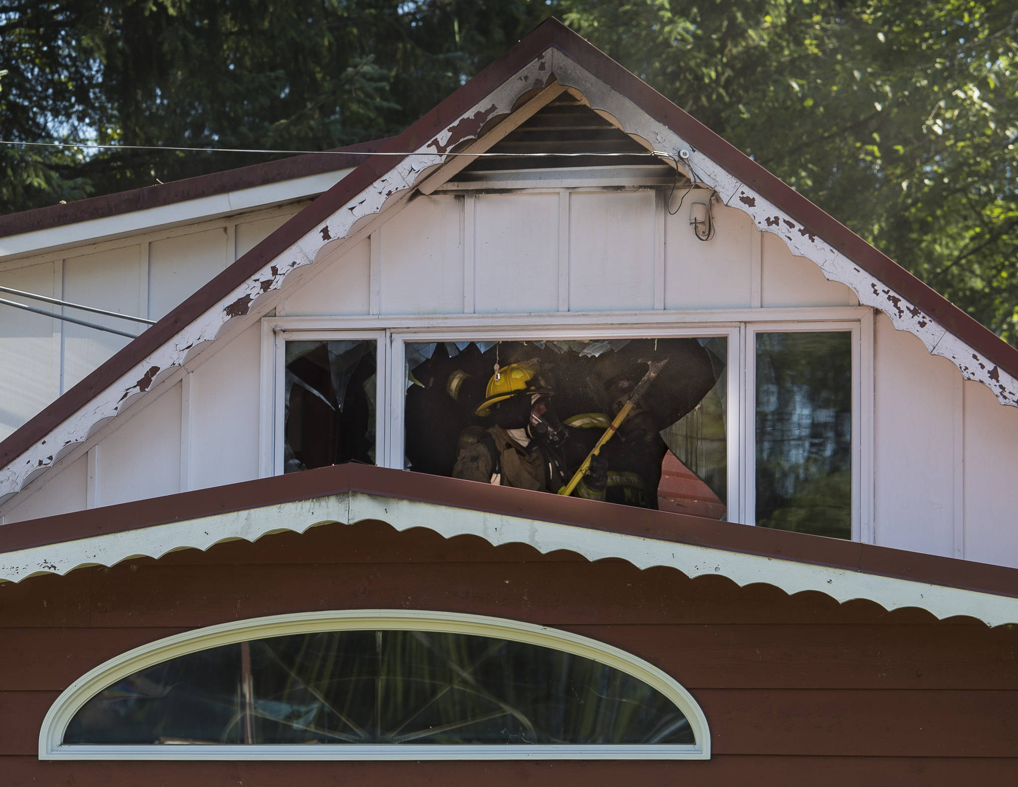 Capital City Fire/Rescue firemen open up a ceiling in an second-story room as they fight a house fire at 8460 Kimberly Street on Friday, July 20, 2018. (Michael Penn | Juneau Empire)