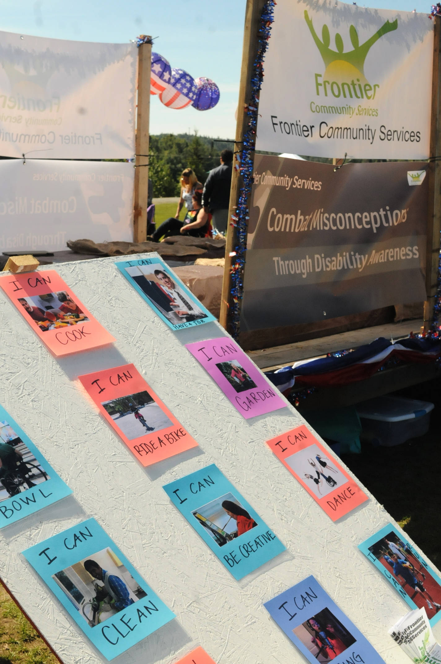 Photos of people who experience disabilities participating in various activities cover a board at the Disability Pride event at Soldotna Creek Park on Saturday, July 21, 2018 in Soldotna, Alaska. (Photo by Elizabeth Earl/Peninsula Clarion)