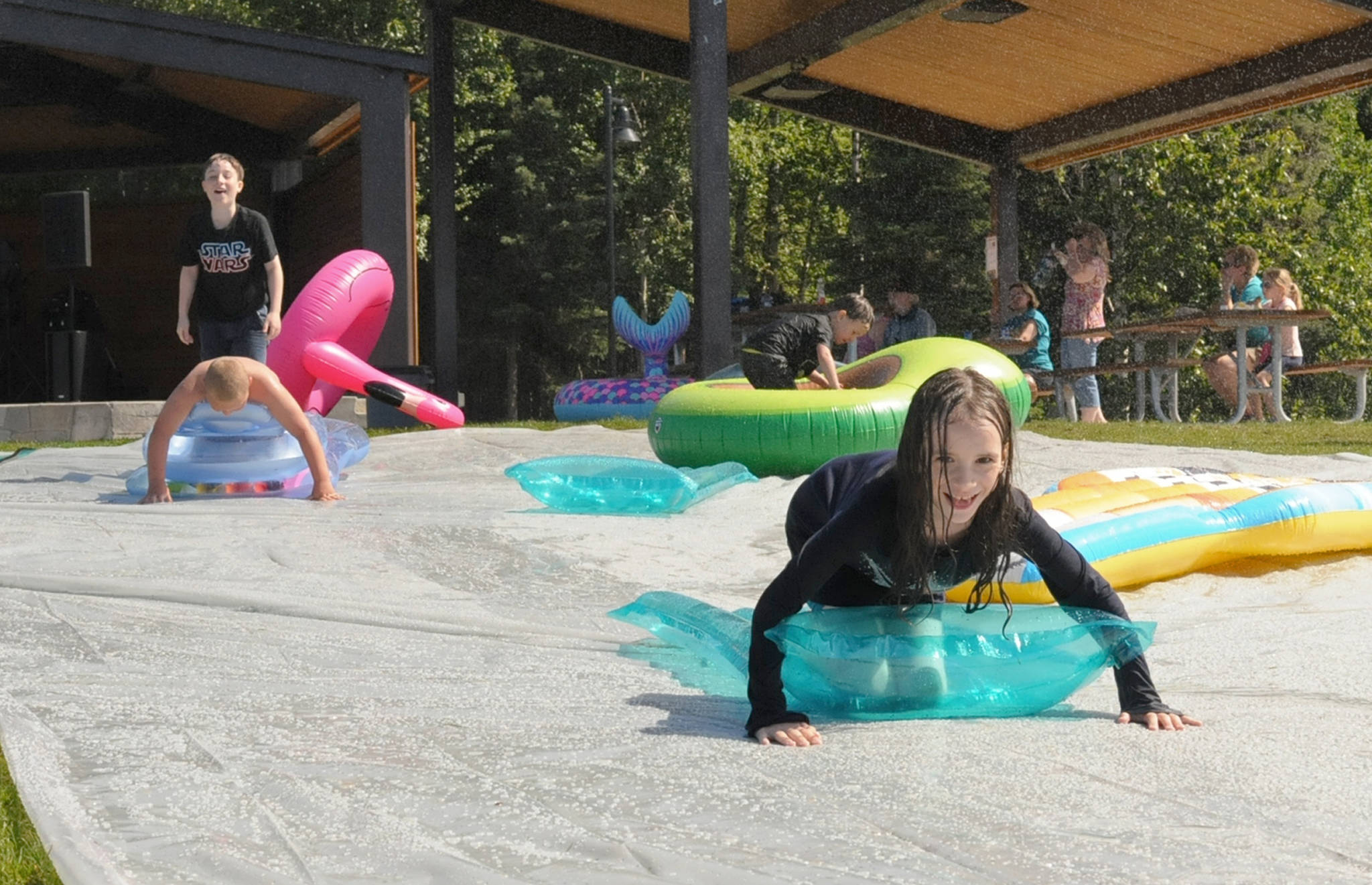 Kids slip and slide down the slip n’ slide at the Disability Pride event at Soldotna Creek Park on Saturday, July 21, 2018 in Soldotna, Alaska. (Photo by Elizabeth Earl/Peninsula Clarion)