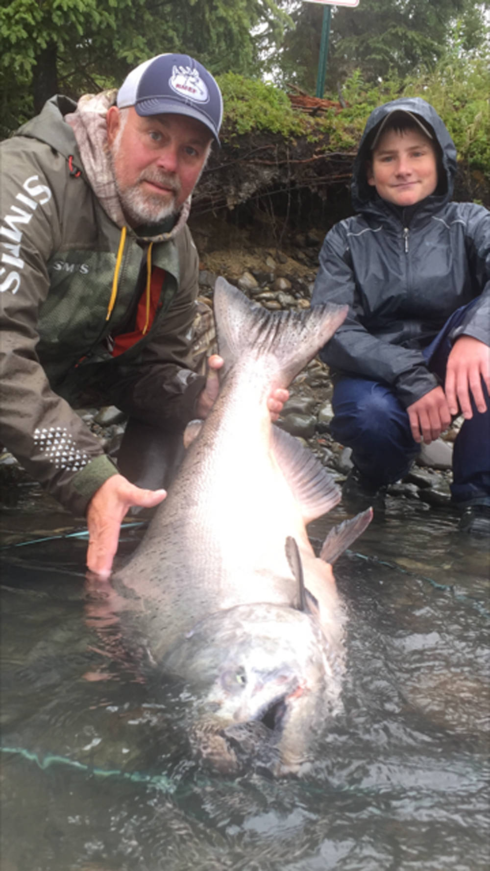 Wet and Wild Alaska Fishing owner and guide Jeff Moore (left) and Tobias Hindman of Iowa (right) pose with the king salmon Hindman caught and released on the Kenai River on Tuesday, July 24, 2018 on the Kenai River, Alaska. The king salmon measured 50 inches long and 34 inches in girth, calculating out to about 78 pounds, Moore said. The king gave Hindman a fight, jumping in and out of the water six times and going under the boat numerous times before he landed and released it. (Photo courtesy Jeff Moore)