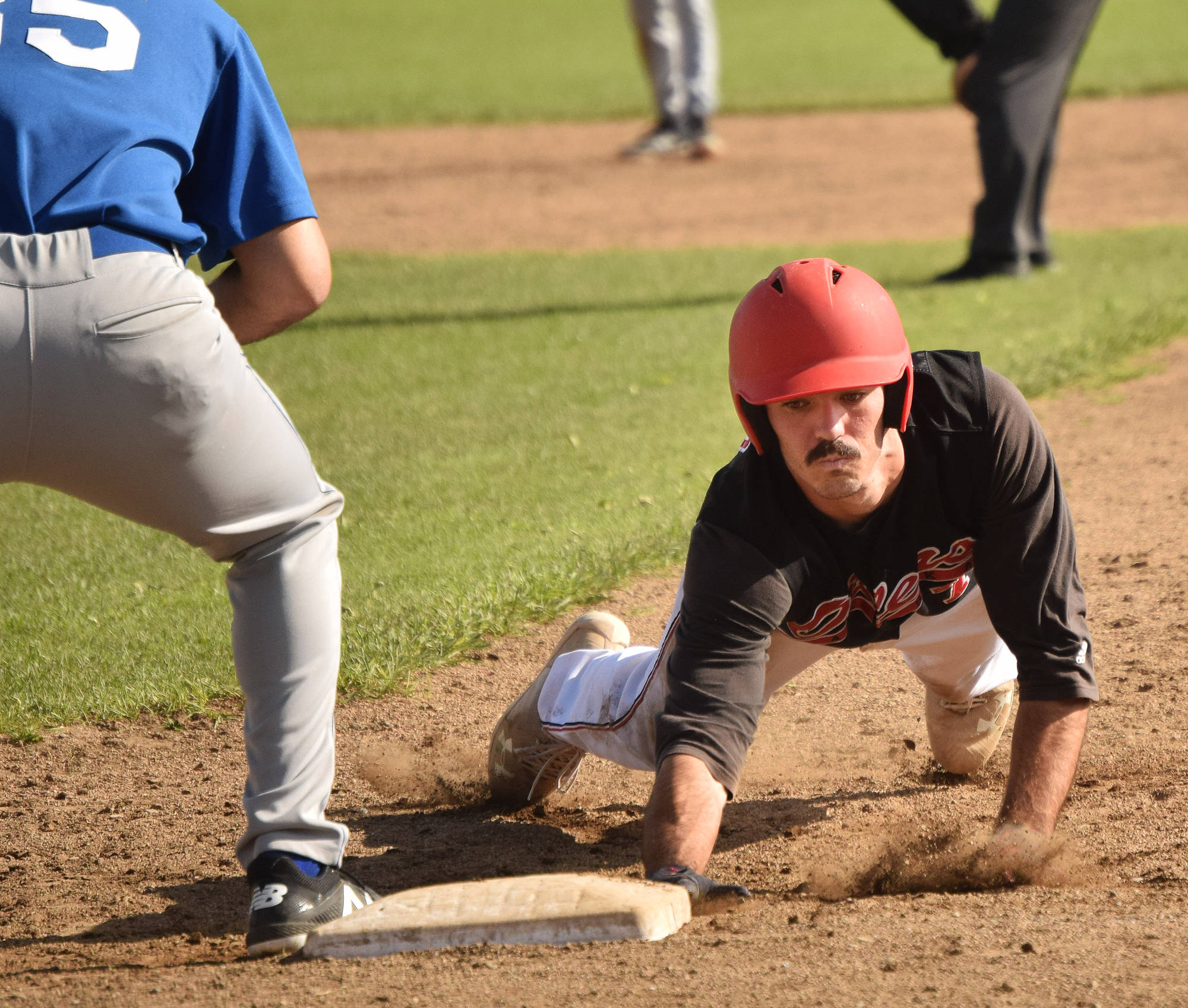 The Peninsula Oilers’ Ryan Novis touches first base just ahead of Anchorage Glacier Pilots first baseman Aaron McCann, Friday at Coral Seymour Memorial Park in Kenai. (Photo by Joey Klecka/Peninsula Clarion)