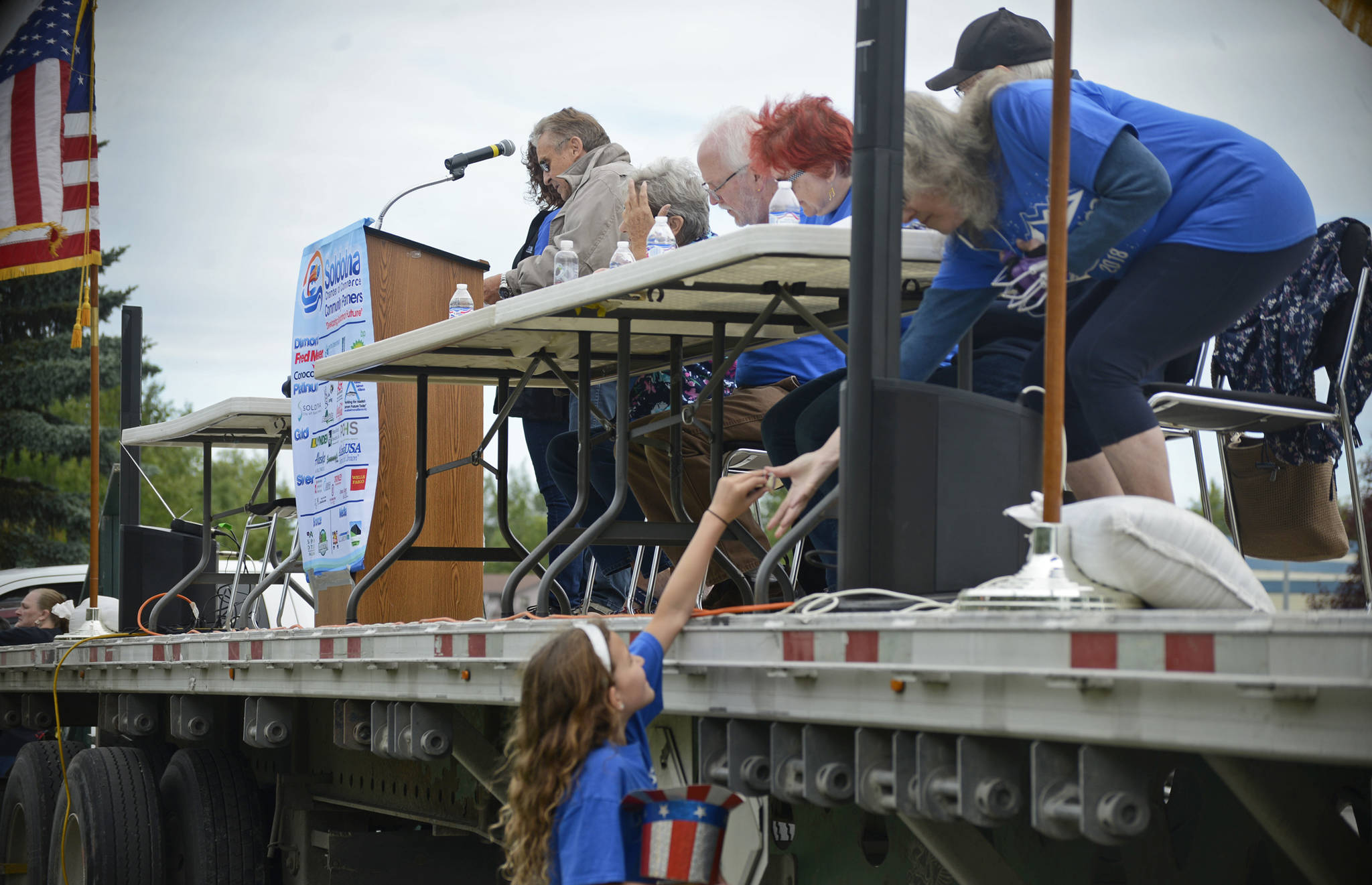 A young Progress Days parade volunteer distributes some candy to the parade judges on Saturday, July 28, 2018 in Soldotna, Alaska. The parade kicks off the weekend-long event celebrating Soldotna’s history, with a market on Saturday and Sunday in Soldotna Creek Park and a concert Saturday night followed by a free community barbecue Sunday. (Photo by Elizabeth Earl/Peninsula Clarion)