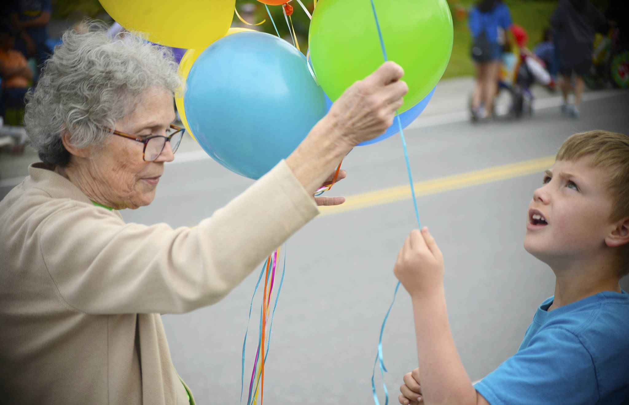A volunteer in Heritage Place’s entry in the Progress Days parade hands a balloon to a young spectator on Marydale Avenue on Saturday, July 28, 2018 in Soldotna, Alaska. The parade kicks off the weekend-long event celebrating Soldotna’s history, with a market on Saturday and Sunday in Soldotna Creek Park and a concert Saturday night followed by a free community barbecue Sunday. (Photo by Elizabeth Earl/Peninsula Clarion)