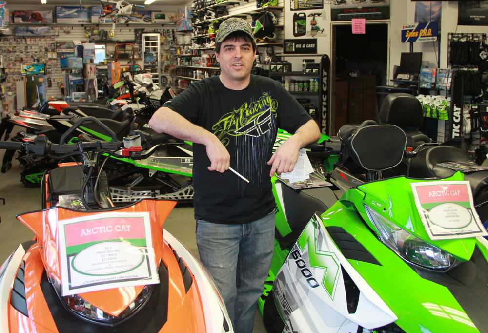 Photo by Dan Balmer Peninsula Clarion Arctic Motorsports owner Lane Giesler stands next two pro model Arctic Cat snowmobiles in his Soldotna shop Feb. 5. Giesler said the entire snow machine industry in Alaska has suffered due to the lack of snow this winter.