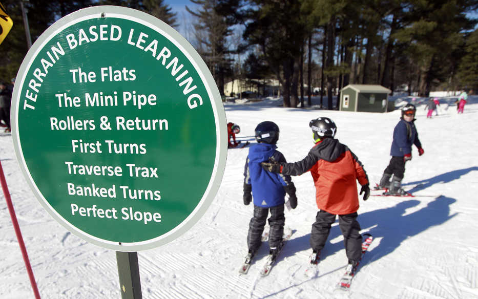 In this photo taken Thursday Jan. 30, 2014 beginner skiers make their way to the terrain-based learning center for new skiers at Cranmore Mountain ski area in North Conway, N.H. Instead of teaching new skiers how to stop first, terrain-based skiing teaches new skiers skills with banks, berms, and bumps that naturally slow them down without sliding down the mountain out of control. (AP Photo/Jim Cole)