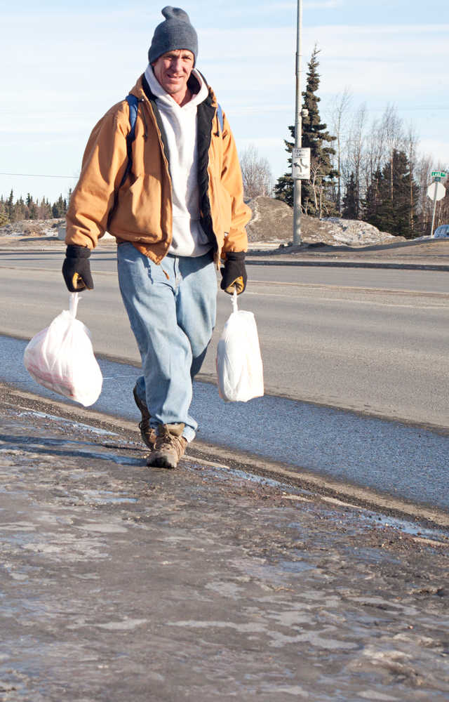 Photo by Rashah McChesney/Peninsula Clarion  Thom Nelson, of Kenai, walks along the Kenai Spur Highway with his groceries Tuesday Feb. 25, 2014 in Kenai, Alaska. Nelson said he was enjoying the beautiful day.