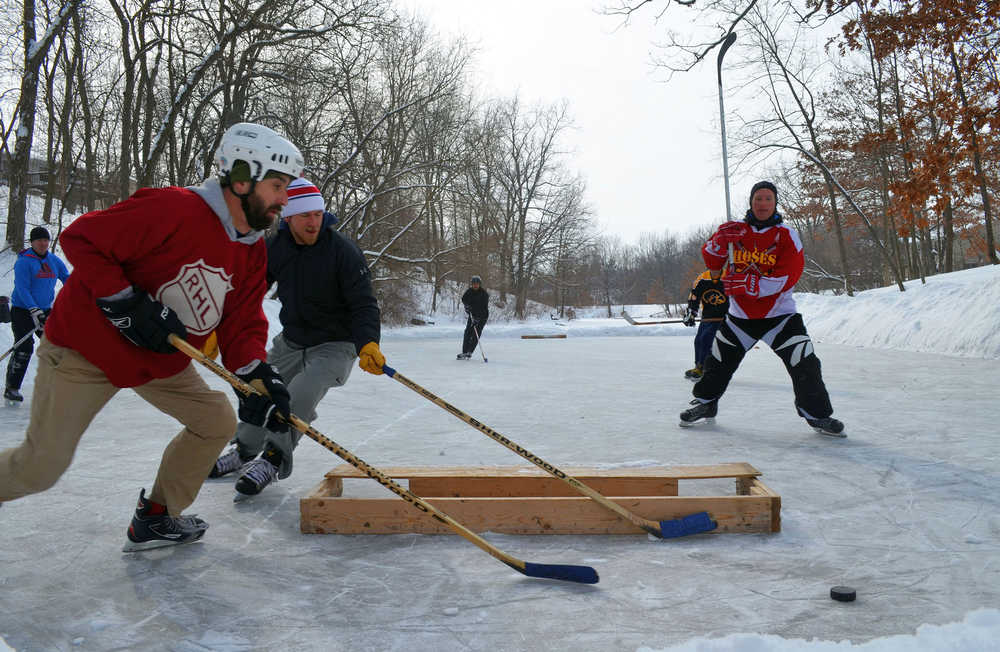 Ed Yankowski, left, and Tommy Haines, rear left, chase the puck Sunday, Feb. 9, 2014 at what has been nicknamed Greedy's Pond in Coralville, Iowa.  Last winter, Coralville resident David Greedy began clearing the snow off this secluded pond at the bottom of a tree-lined ravine that runs through his neighborhood. Since then, it's been a winter meet-up spot for the small but growing group of pond hockey lovers.  (AP Photo/Iowa City Press-Citizen, Josh O'Leary)  NO SALES
