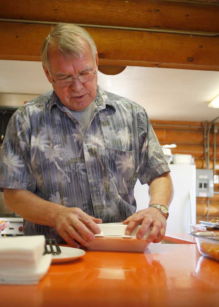 Photo by Rashah McChesney/Peninsula Clarion Volunteer Pat "Juney" Mullan packages a container of fry bread for a customer Friday March 7, 2014 at Ft. Kenay in Kenai, Alaska. Mullan, who spent a lot of his time joking with customers at "Fry Bread Friday" introduced himself as Feodor, Chelawek and Juney before settling on Pat.