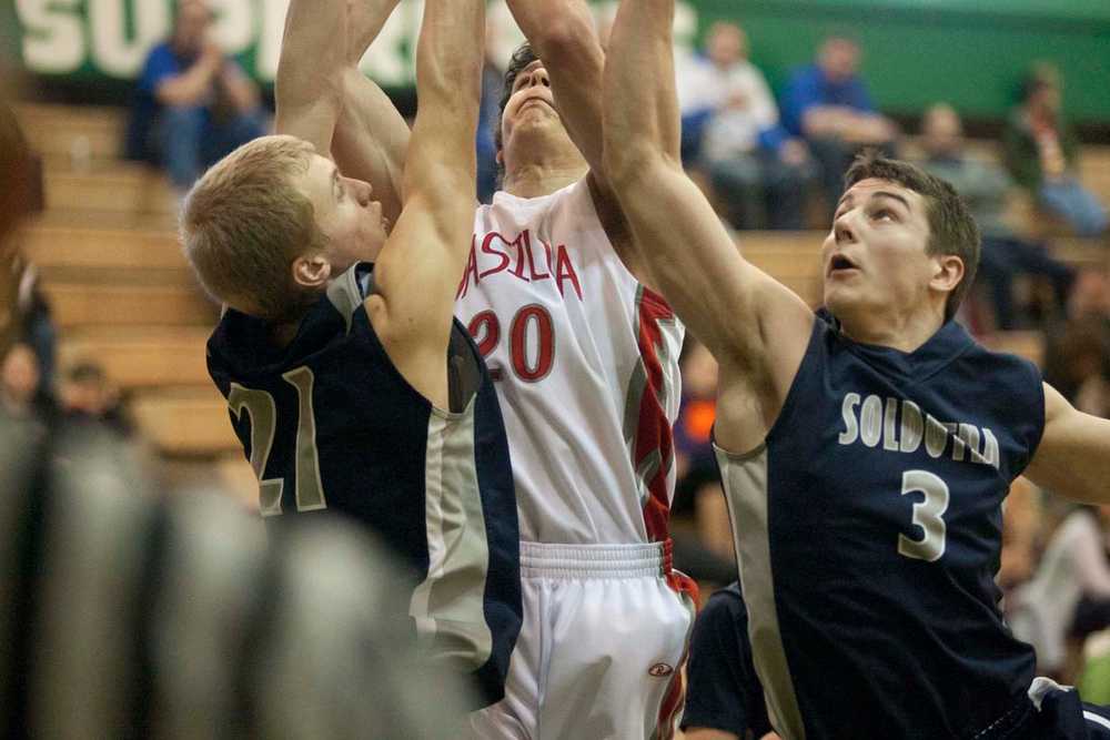 Soldotna's Austin Kruse and River Calloway get in front of Zack Garnett's shot during a win over the Warriors at Colony High.