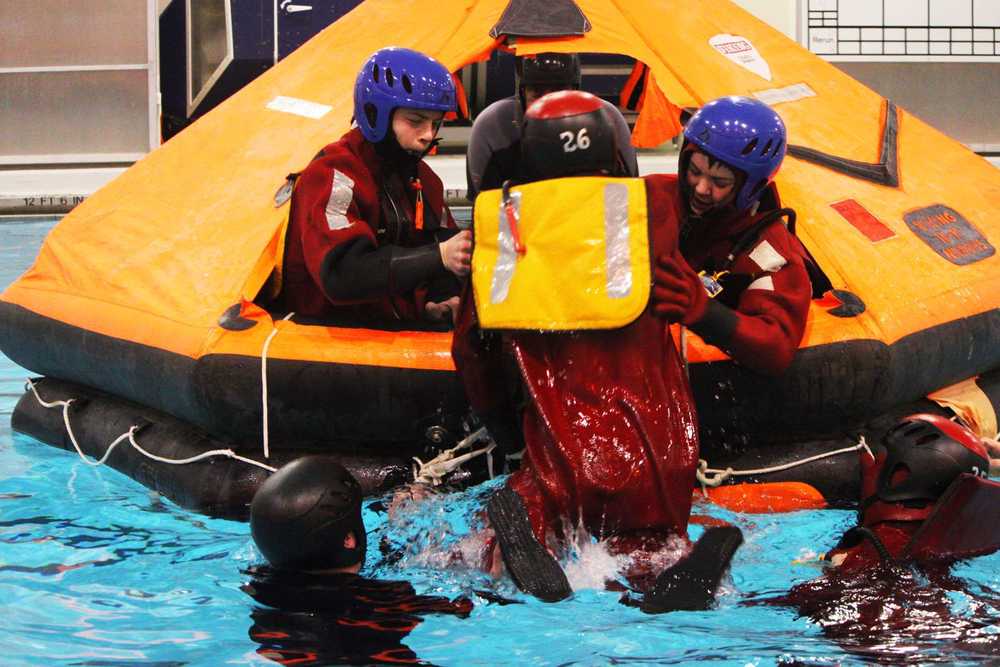 Classmates Donovan Orth and Seth Desiena learn to pull their peer out of cold water and into the safety of a life raft. Photo by Kelly Sullivan/ Peninsula Clarion