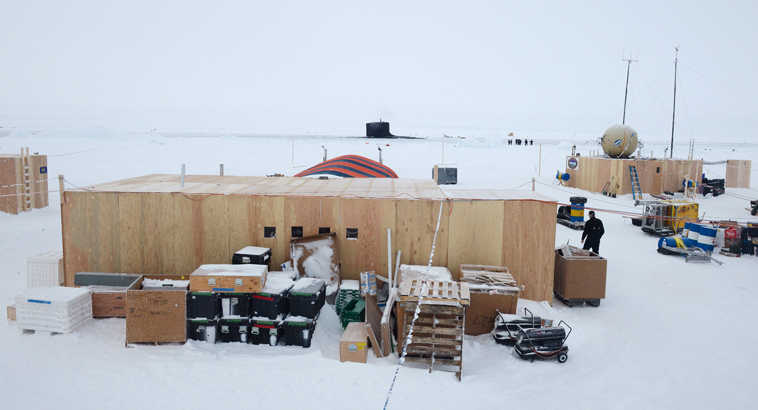 In this Saturday, March 22, 2014 photo provided by the U.S. Navy, the Virginia-class attack submarine USS New Mexico, background, surfaces through the arctic ice near Ice Camp Nautilus, north of Alaska. Cracks in polar sea ice are prompting the Navy to break down an ice camp north of Alaska that provided support for an exercise involving submarines. The Navy says in a release Monday, March 24, 2014, that the commander of submarine forces ordered an early end to Ice Camp Nautilus because shifts in winds created instabilities in ice floes. (AP Photo/U.S. Navy, Joshua Davies)