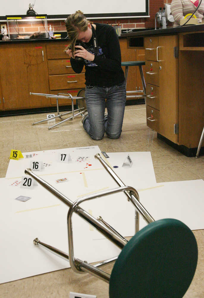 In this photo taken on Wednesday, March 19, 2014, Reilly Fahrenholz takes photographs of evidence at a mock crime scene for Adams Central's Forensic Science course in Hasting, Neb., where students will try to solve a murder mystery. (AP Photo/The Hastings Tribune, Amy Roh)