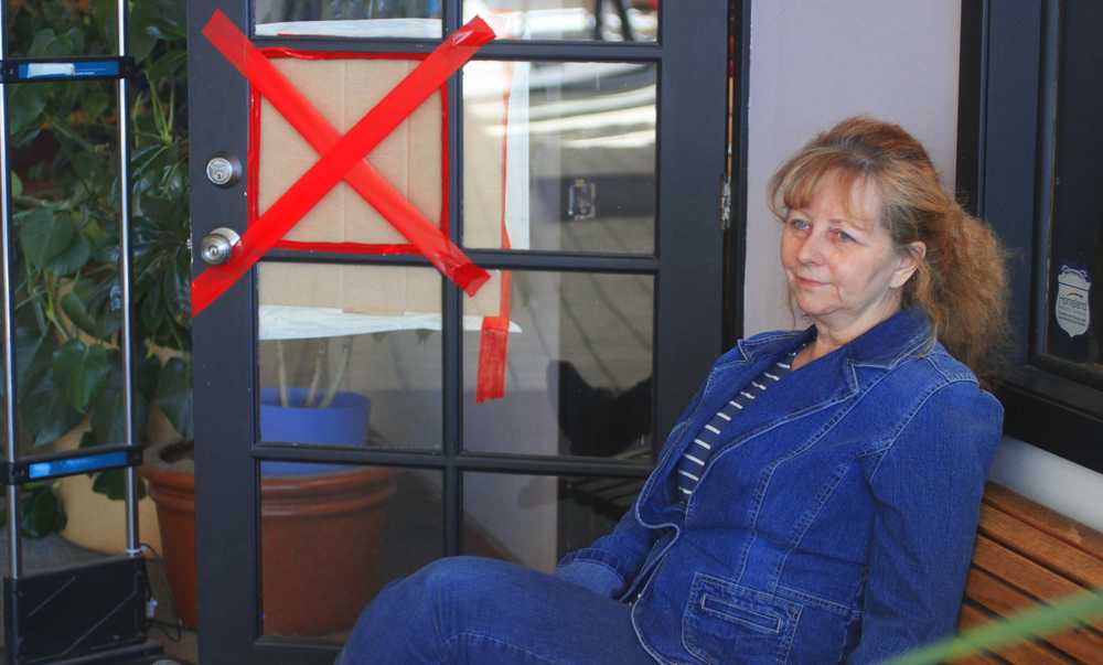 Laone Benton sits beside the shattered window that was broken in attempt to steal money from the store she owns, Tuesday, April 1, At Laone's Kenai River Purse.