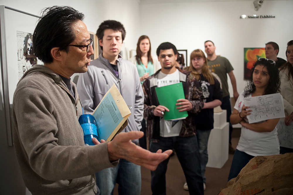 Photo by Rashah McChesney/Peninsula Clarion  Cam Choy, associate professor of Art at Kenai Peninsula College - Kenai River Campus, talks to one of his classes about a watercolor piece in the student art show Wednesday April 16, 2014 in Soldotna, Alaska.  The show will be on display through May 2 in the Gary L. Freeburg art gallery in the Brockel building.
