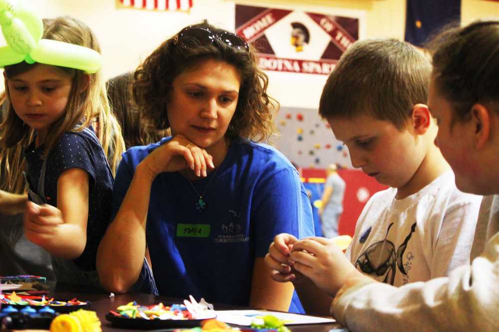 Photo by Kelly Sullivan/ Peninsula Clarion Emma Updike, Tonja Updike, Emma Updike and Ellyce Woodward work at a craft table during the Autism Walk, Saturday, April 19, at Soldotna Middle School.