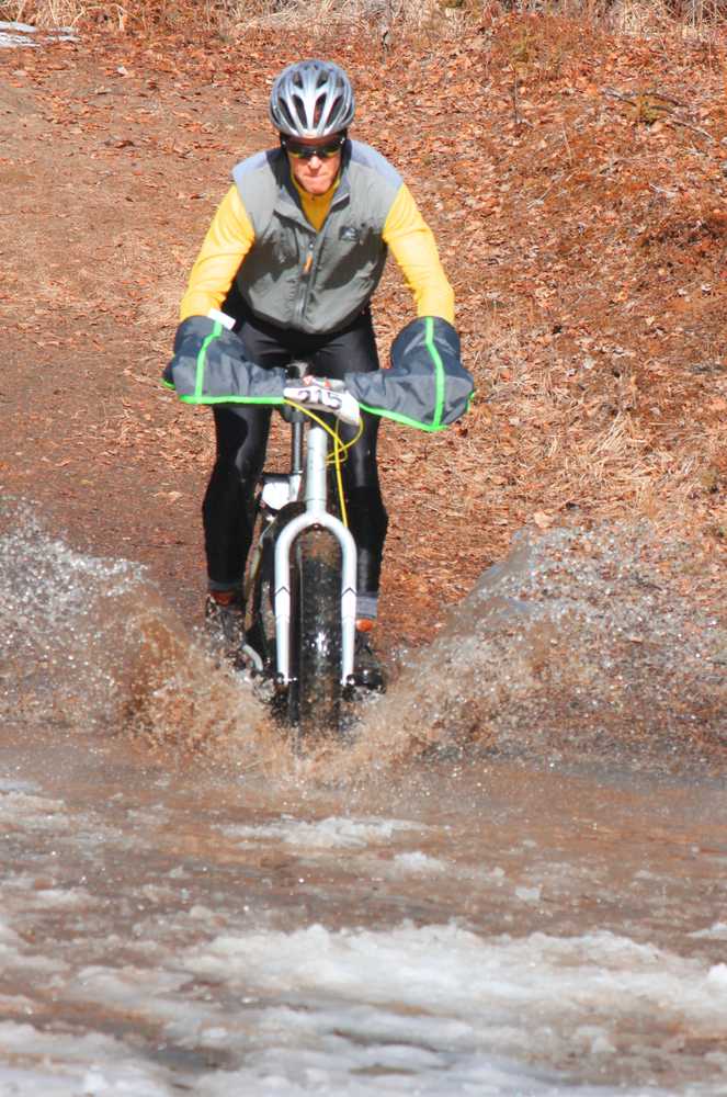 Photo by Kelly Sullivan/ Peninsula Clarion Doug Armstrong rode downhill into a muddy, pool of melting ice on Wolverine trail, Saturday, April 19, at the Tsalteshi Trail.