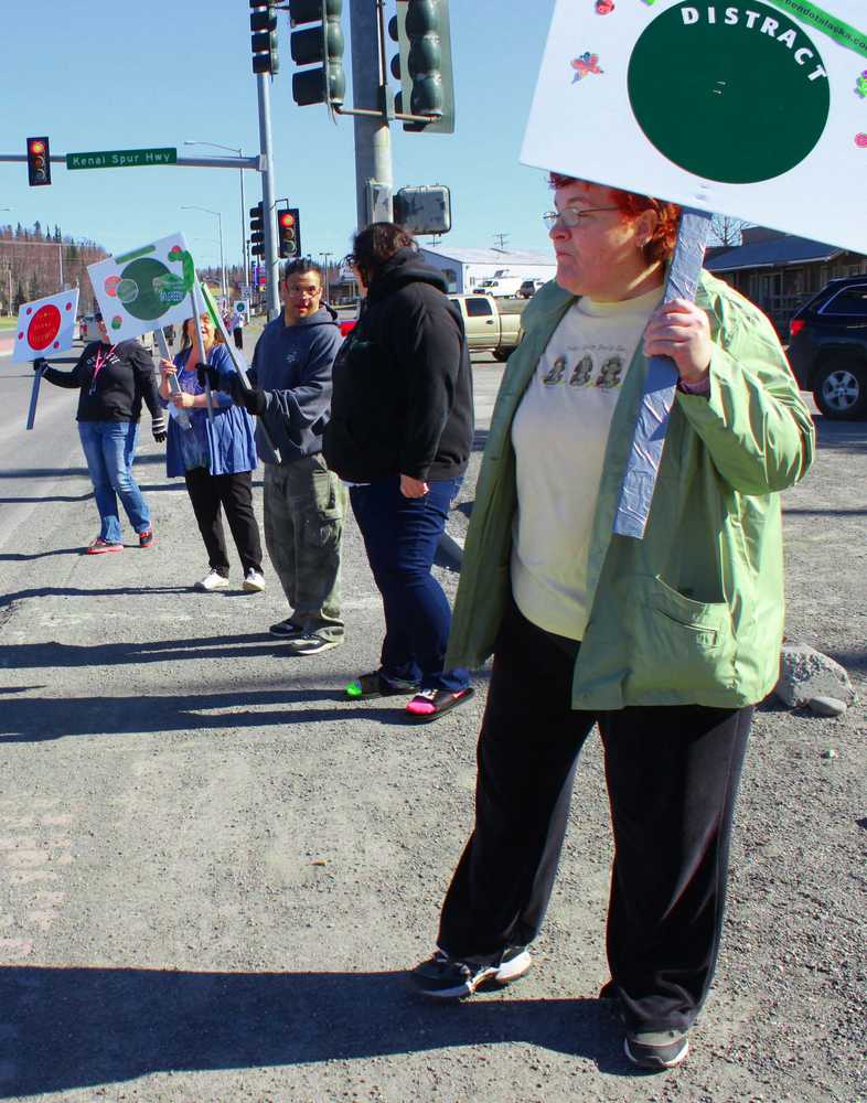 Photo by Kelly Sullivan/ Peninsula Clarion Elijah Stafford, Haley Baxter and Susie Swafford  wave signs and pass out candy to raise awareness for the local launch of the Green Dot Violence Prevention Strategy, headed by LeeShore Center, Tuesday, April 22, on the Kenai Spur Highway.