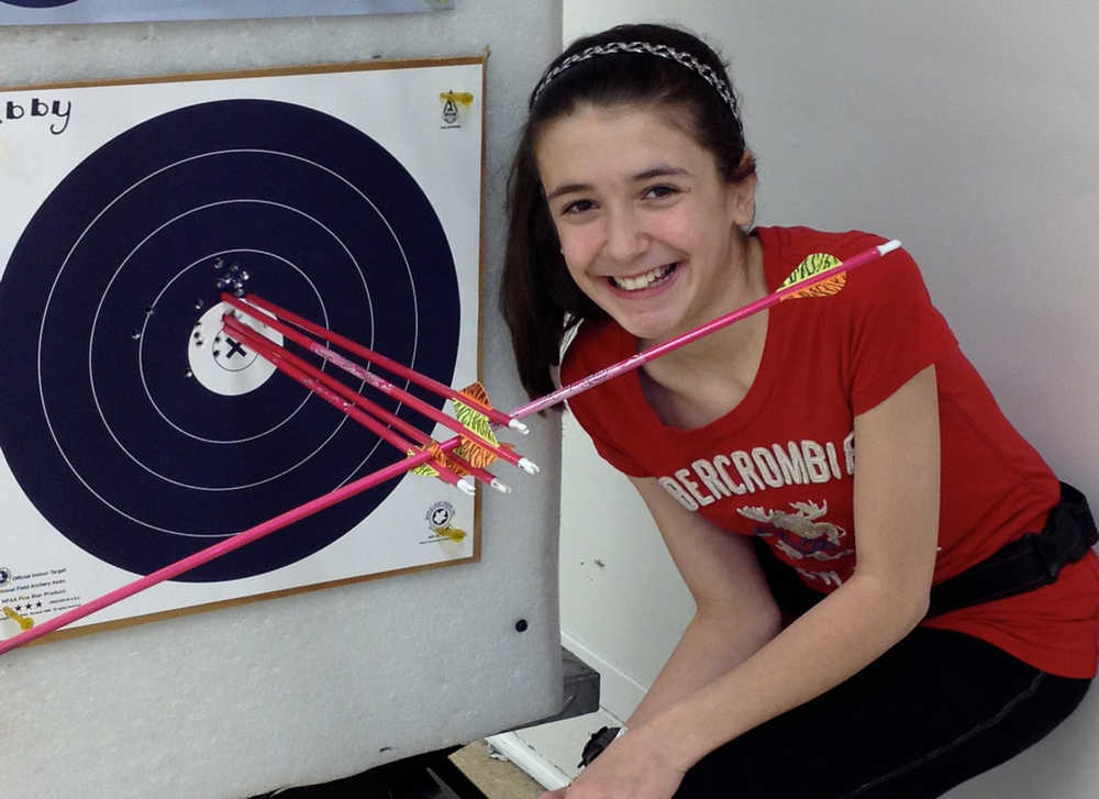 Photo courtesy DiPaolo family Abby DiPaolo poses next to her target from the  from the 2013 State Indoor 5 Spot Tournament. The sideways arrow actually hit another arrow and pierced the vein of the arrow.