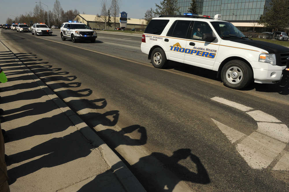 Firefighters stand at attention and salute as the procession for two slain Alaska State Troopers arrives at the State Medical Examiners office in Anchorage, Alaska on Friday, May 2, 2014. Troopers Sgt. Patrick "Scott" Johnson and Gabriel "Gabe" Rich were killed in the line of duty in Tanana, Alaska on Thursday, May 1, 2014. (AP Photo/Anchorage Daily News, Bob Hallinen)