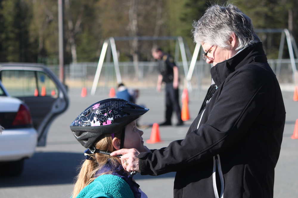 Photo by Kelly Sullivan/Peninsula Clarion Shelby Moore bought a helmet at the Bike Rodeo, and needed help adjusting the straps, Friday, May 9, at Mountain View Elementary School.
