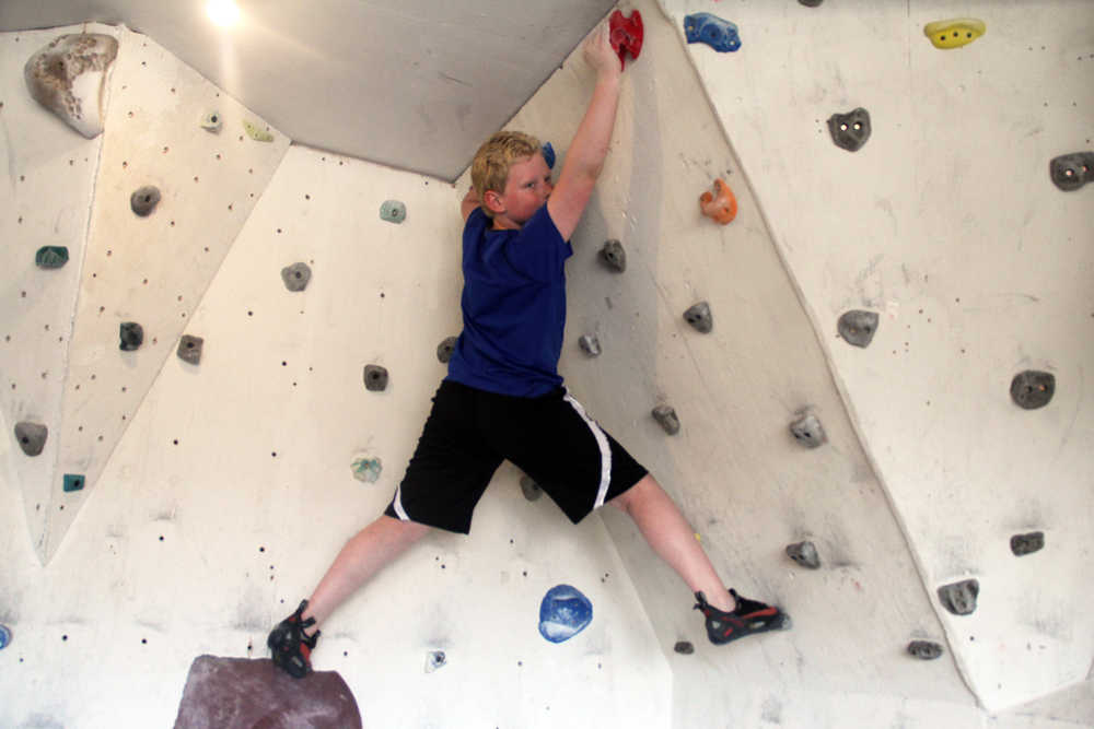 Photo by Dan Balmer/Peninsula Clarion Hunter Sundberg, 11, looks to get his footing on a rock wall built in the garage of Natalie and Nic Larson in Soldotna. The Larson's started teaching rock climbing sessions to several kids in March and are accepting new students for summer sessions beginning June 9.