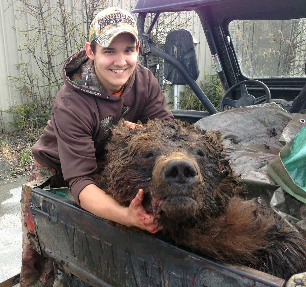Clarion staff photo Daniel Rosin of Soldotna shows off the brown bear he took down while bowhunting near Skikok Lake on May 6. Rosin only needed one arrow to kill the 9-foot, 750-pound bear he shot from a stand 25 feet in the air from a distance of 20 yards away.