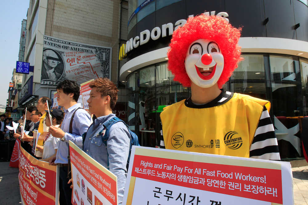 A protester dressed as Ronald McDonald participates in a rally to demand higher wages for fast-food workers outside a McDonald restaurant in Seoul, South Korea, Thursday, May 15, 2014. About 30 labor union members joined the global action to ask higher pay for part-time workers.(AP Photo/Ahn Young-joon)
