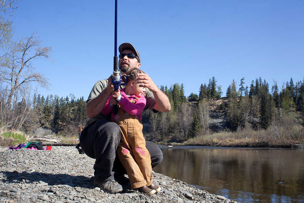 Photo by Rashah McChesney/Peninsula Clarion  Charlie Black chats with a friend as his daughter Zoe Black, 4, tries to get back to fishing in the Anchor River Saturday May 17, 2014 near Anchor Point, Alaska.