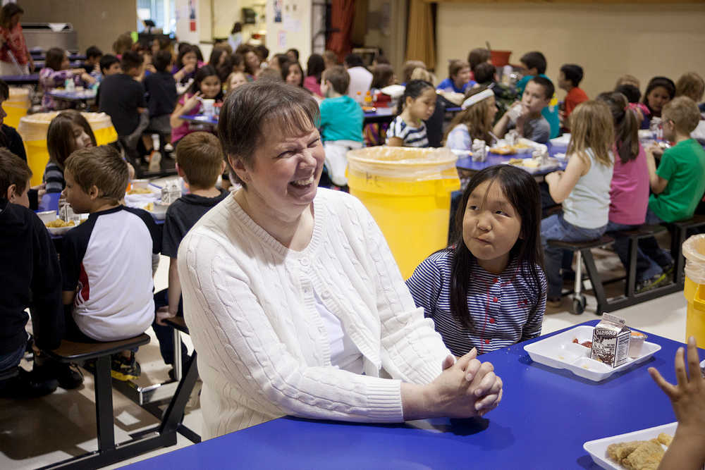 Photo by Rashah McChesney/Peninsula Clarion  Norma Holmgaard, retiring principal of Mountain View Elementary school, chats with a table of students during lunch Friday May 16, 2014 in Kenai, Alaska.