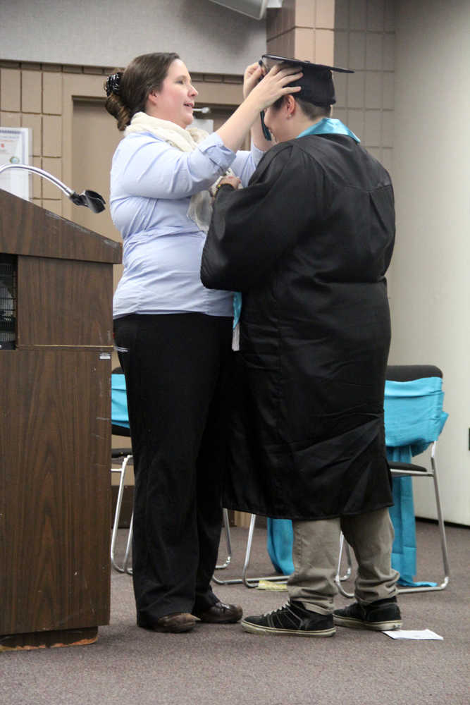 River City Academy Principal Dawn Edwards-Smith adjusts graduate Shelby Fletcher's mortarboard one last time after knocking it off during a hug at the school's graduation ceremony at the Soldotna Regional Sports Complex on Wednesday. Photo by Kaylee Osowski/Peninsula Clarion