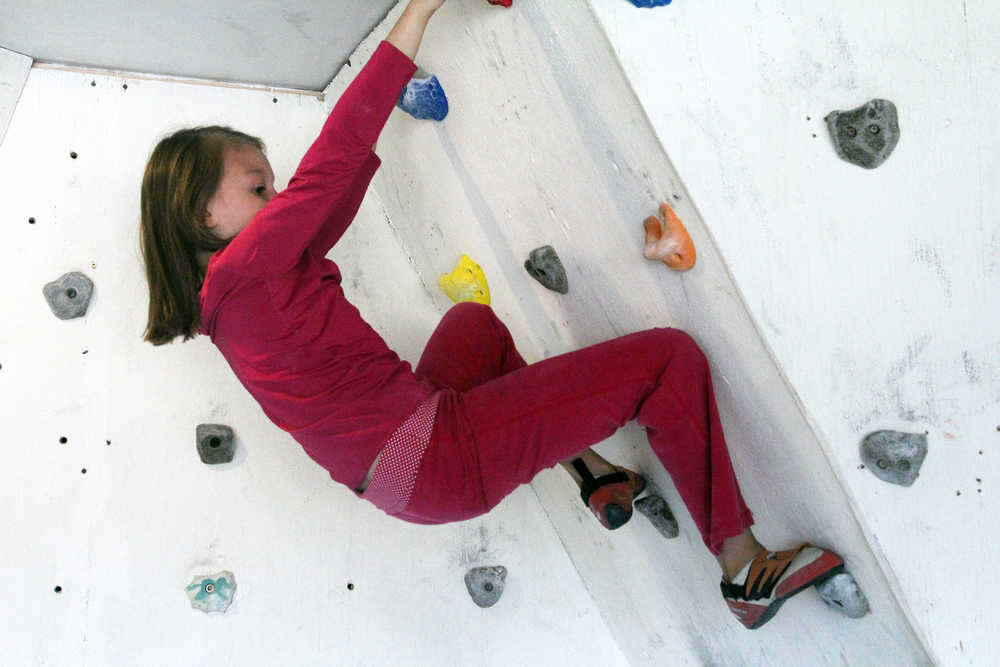Photo by Dan Balmer/Peninsula Clarion Mia Gridley, 9, holds onto the sloped rock wall built in her familiy's garage. Her mom Natalie Larson teaches rock climbing for kids with one-hour sessions and is available from noon to 7 p.m. Monday - Thursday.