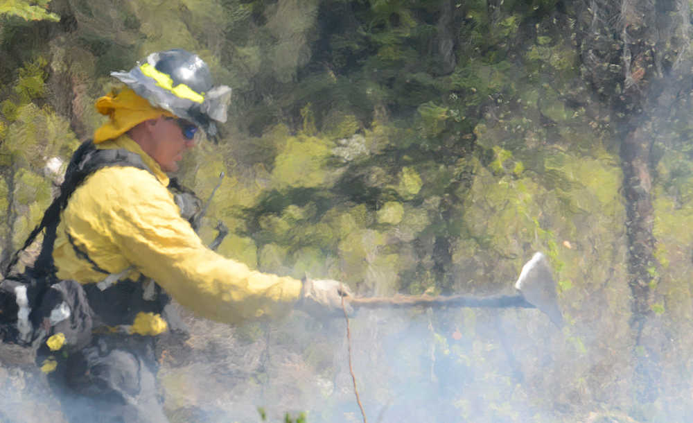 Photo by Rashah McChesney/Peninsula Clarion Josh Thompson, firefighter with Central Emergency Services on the Kenai Peninsula, throws brush into a fire along Funny River Road Thursday May 22, 2014 as the group works to control the burning Funny River wildfire which has consumed more than 63,000 acres of Kenai National Wildlife Refuge land.