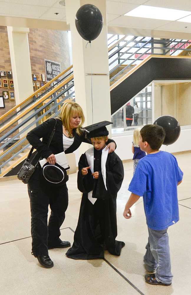 Photo by Rashah McChesney/Peninsula Clarion Catherine Carmody adjusts a graduation gown on her son Gavin Carmody who took it from his graduating senior brother Gage Carmoday Monday May 20, 2014 during the Nikiski Middle-High School graduation in Nikiski, Alaska.