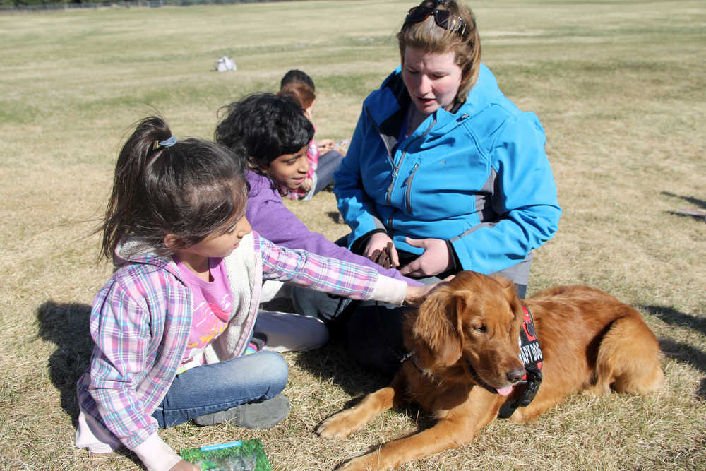 Kindergartener Jenesys Vandermartin (left) and fourth grader Shraddha Davis (center) pet Lucy, the dog, as Katie Moon (right), Lucy's owner, sits with them. The two students read to Lucy at Kalifornsky Beach Elementary School in Soldotna on Tuesday, May 20. Photo by Kaylee Osowski/Peninsula Clarion