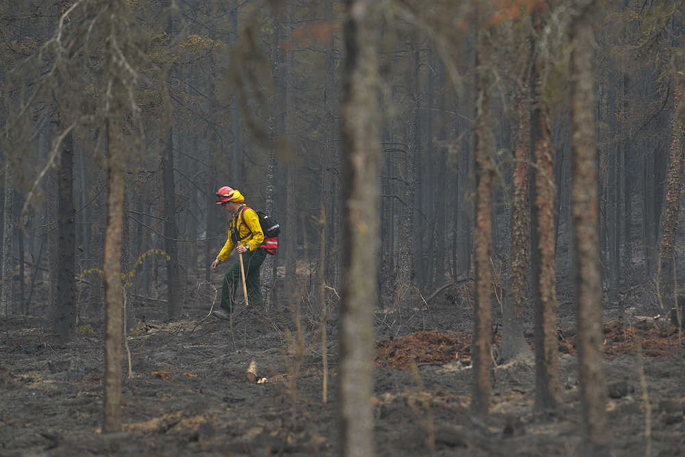 Photo by Rashah McChesney/Peninsula Clarion  Rob Porter, firefighter for Kachemak Emergency Services works to clear a line about 100 feet into a fire line on Funny River Road Tuesday May 27, 2014 in Soldotna, Alaska. Residents who were evacuated from the area have been allowed to return and firefighters are working to put out smoldering piles and burn potential fuel sources to lessen the chance of a hot spot turning into a fire. The area, near mile 9 of Funny River Road, was caught in the Funny River Horse Trail wildfire which has burned 182,209 acres of Kenai National Wildlife Refuge land.