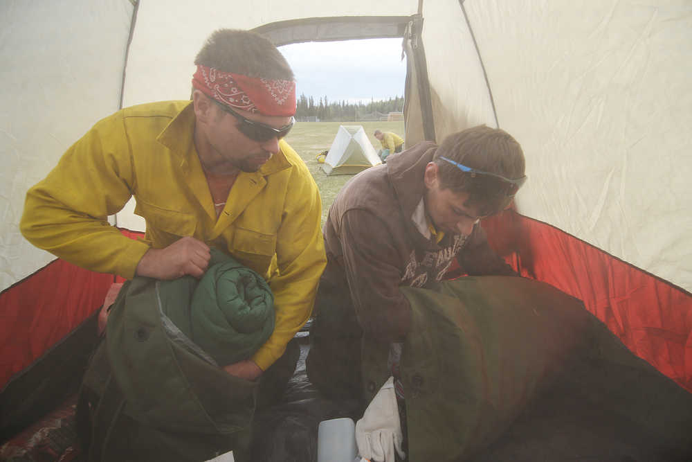 Photo by Rashah McChesney/Peninsula Clarion Firefighters Tim Kulinich and Bogdan Kulikovskiy unpack their bags inside of a tent in the soccer field Monday May 26, 2014 at Skyview High School in Soldotna, Alaska. More than 670 firefighting crew have arrived on the Kenai Peninsula to help combat the 170,000 acre Funny River Horse Trail wildfire.