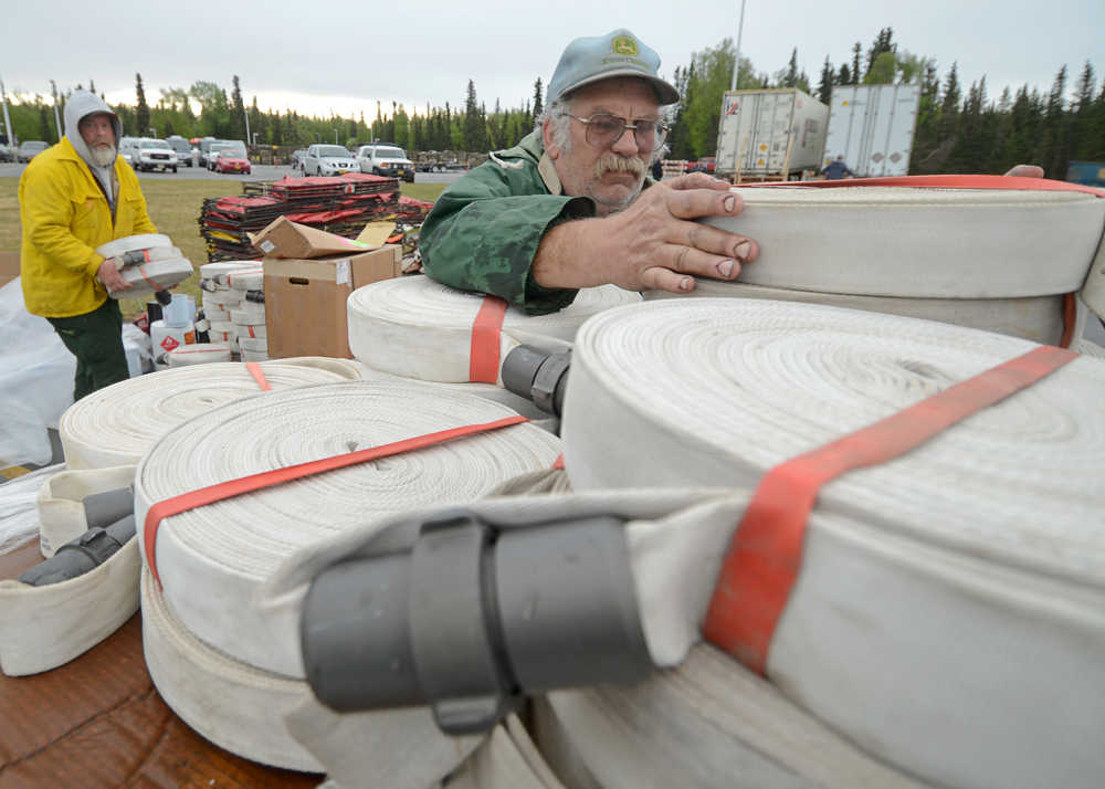Photo by Rashah McChesney/Peninsula Clarion  (left) Scott Johnson, of Ninilchik, and Tom Vangs, of Oregon, stack firehouse on a pallet in the temporary warehouse set up to supply firefighters working on the Funny River Horse Trail wildfire Friday May 30, 2014 in Soldotna, Alaska.
