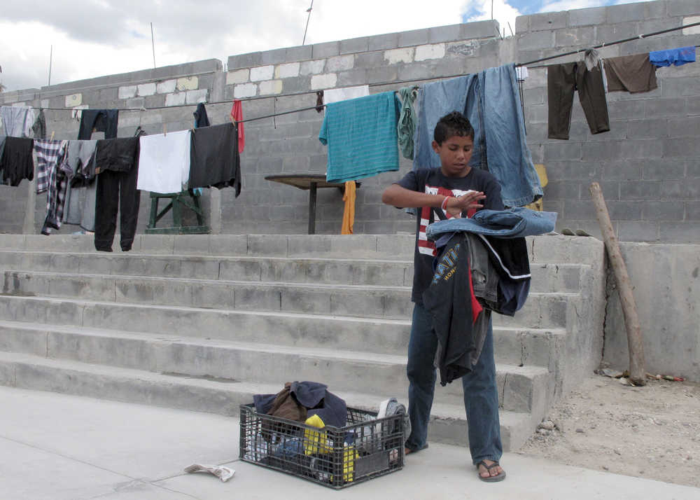 Brian Duran, 14, of Comayagua, Honduras collects his line-dried laundry at the Senda de Vida migrant shelter in Reynosa, Mexico,  June 3, 2014. Duran traveled alone to the U.S.-Mexico border and hopes to soon become one of the more than 47,000 unaccompanied children to enter the United States since Oct. 1, 2013. (AP Photo/Chris Sherman)